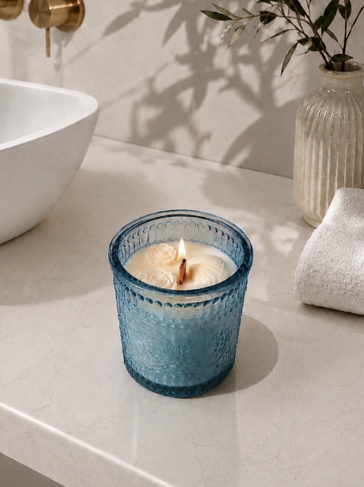 Blue glass rose candle lit on a bathroom counter