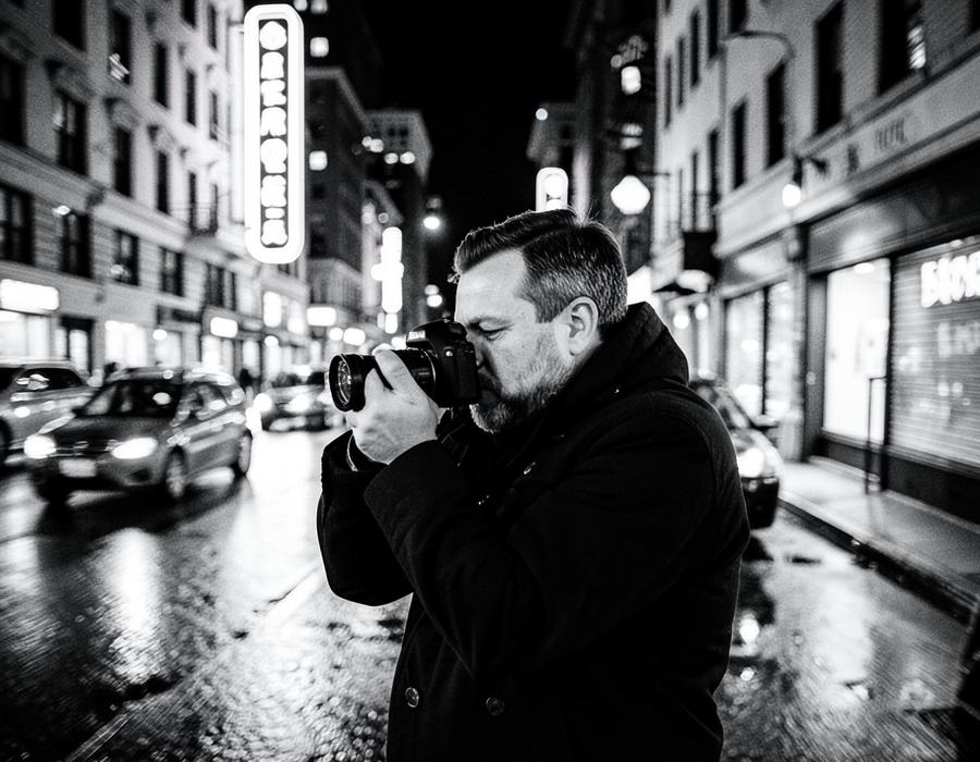 Photographer shooting on a neon-lit street at night